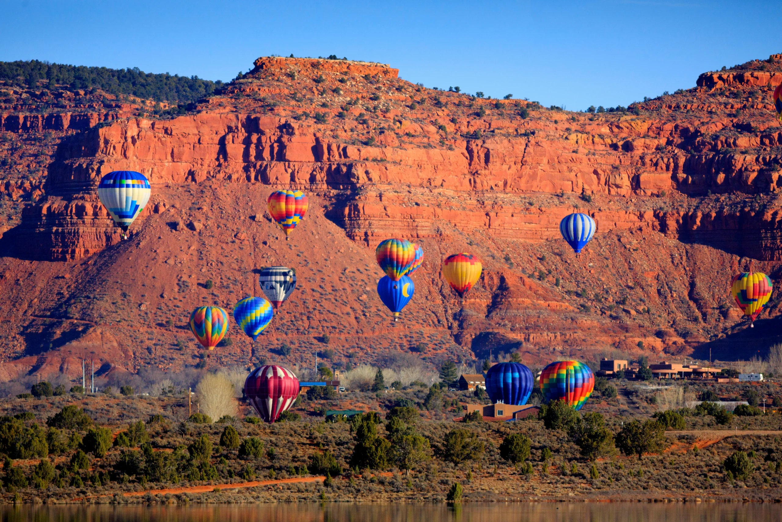 Hot air balloons flying over red rock bluffs during the annual Kanab, Utah Balloons and Tunes Festival